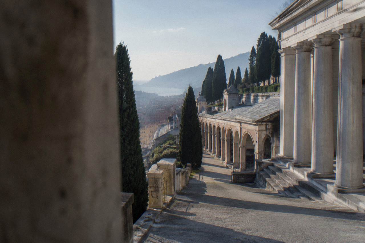 Stone sculptures and cypress trees along a terraced path at a monumental cemetery on a hillside