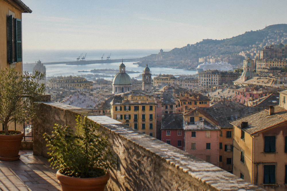 A panoramic terrace overlooking rooftops, a harbour and the sea from a Genoa hillside