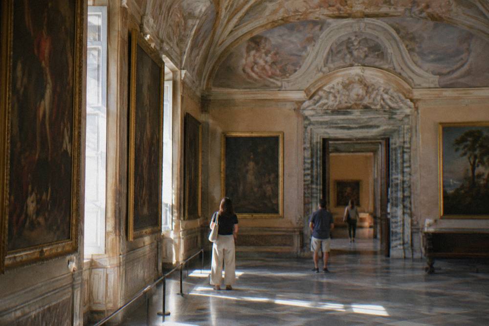 A gallery interior of a Genoa palace museum with paintings and frescoed ceilings