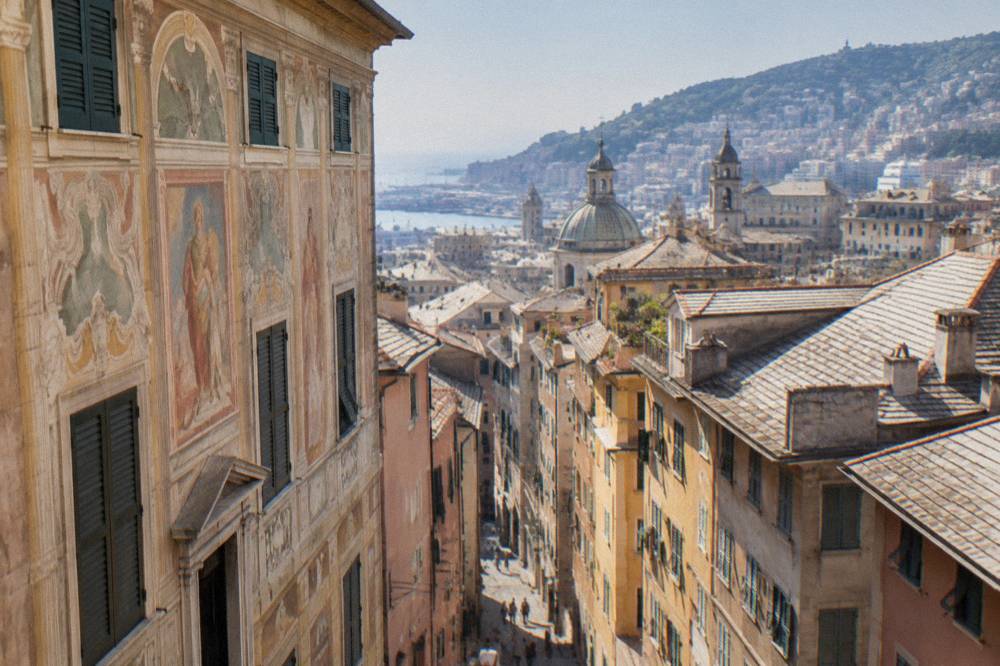 A grand Renaissance palace facade with frescoed walls on a Genoa street