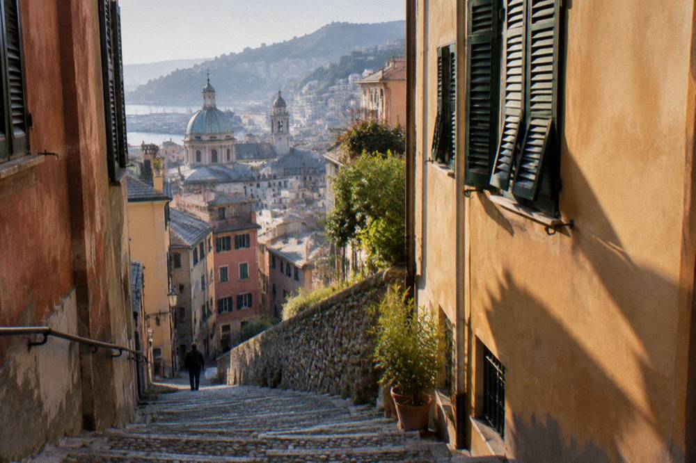 A steep cobbled lane and stone stairs climbing between tall coloured houses in Genoa