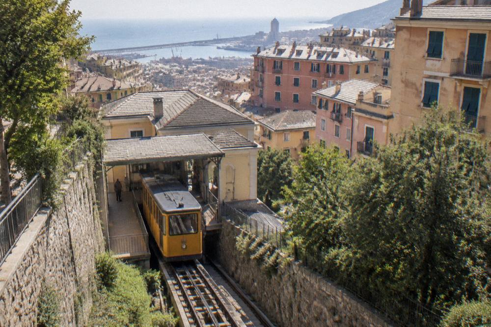 A funicular station platform with a yellow car waiting on steep rails in Genoa