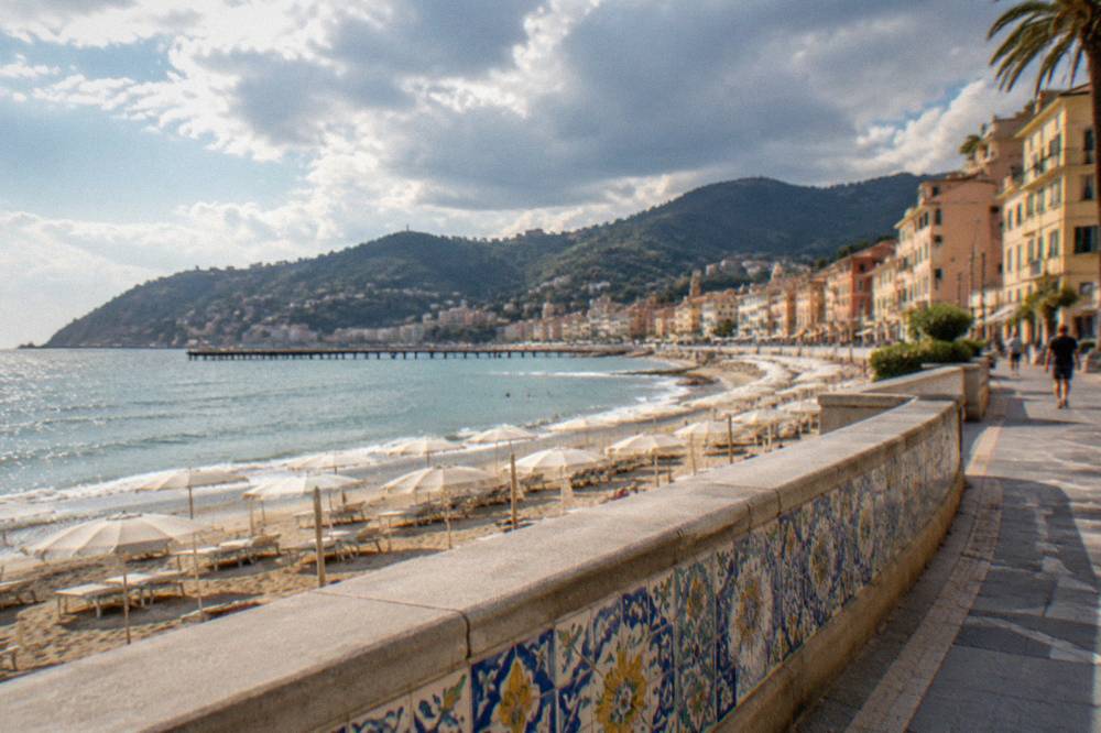 A ceramic-tiled sea wall running beside a seaside promenade in warm afternoon light