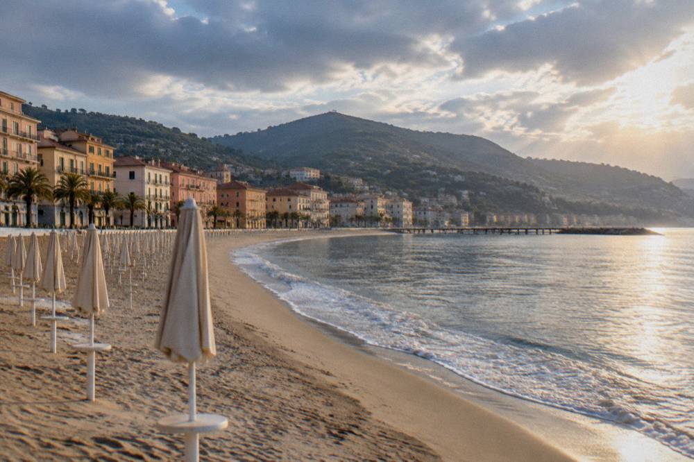 Empty golden sand at sunrise with gentle waves along a Riviera bay