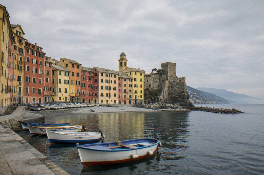 Wooden fishing boats tied up along a stone quay in front of painted buildings