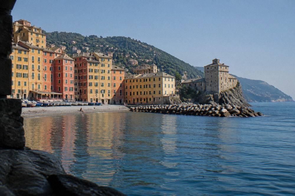 Coastal village seen from the water under a clear sky with wooded headland