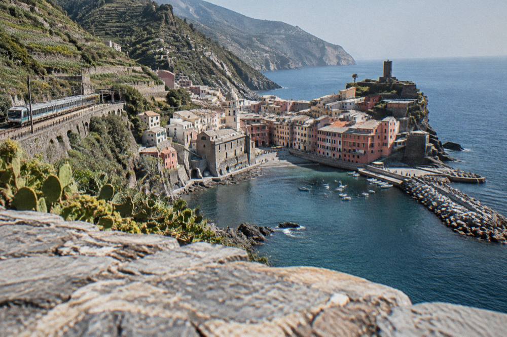 A regional train stopping at a small station above the sea on a terraced coastline