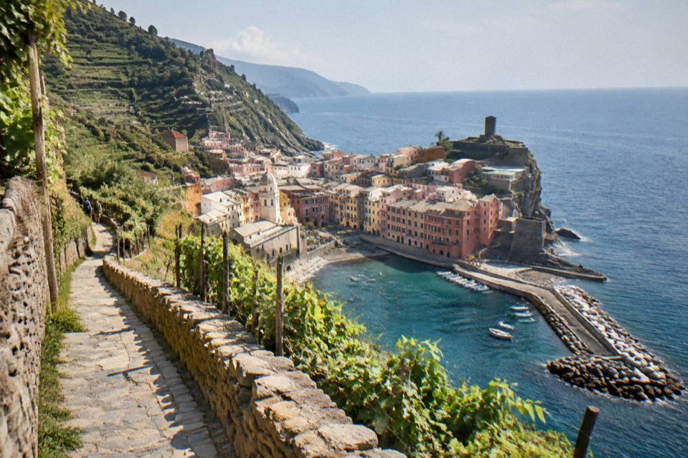 A stone footpath winding between terraced vineyards above the sea
