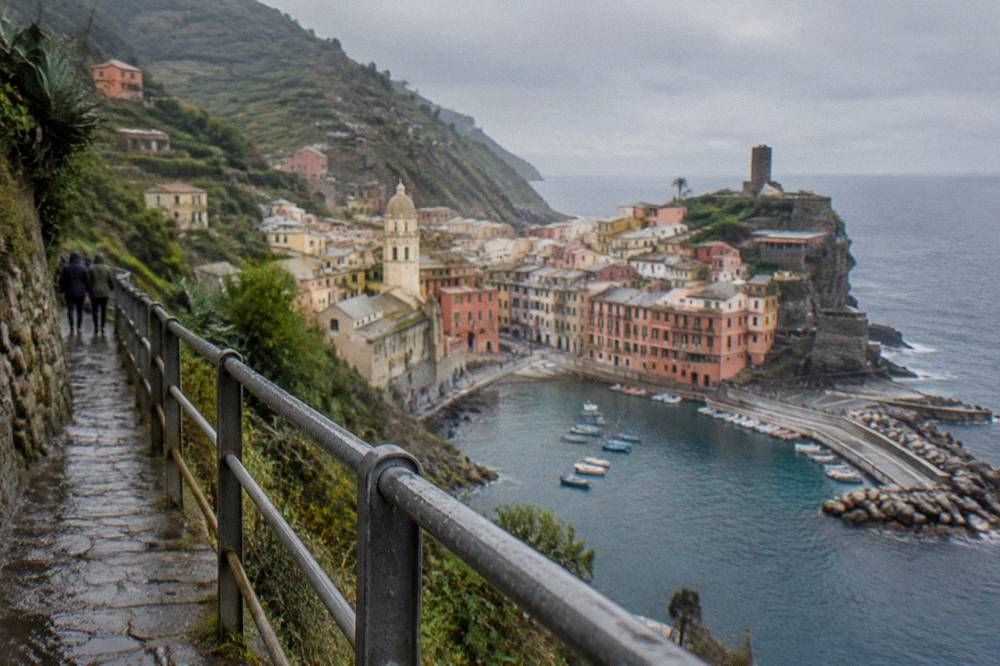 A view along a railed cliffside path above the sea at midday