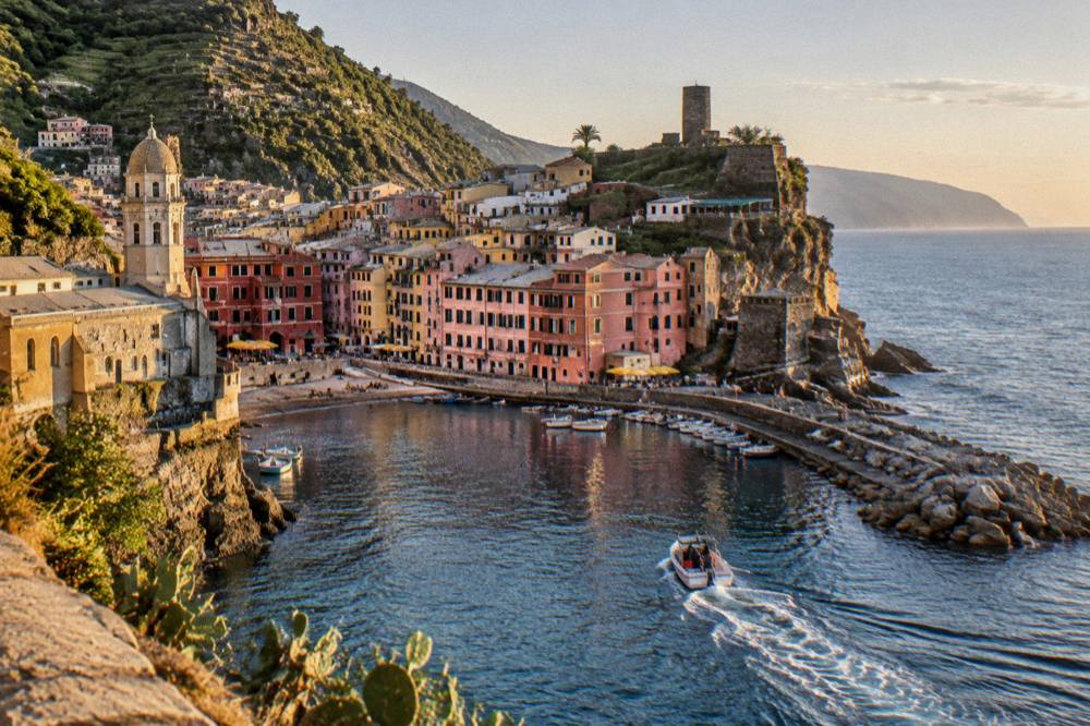 A boat leaving a small harbour at golden hour on the Ligurian Sea