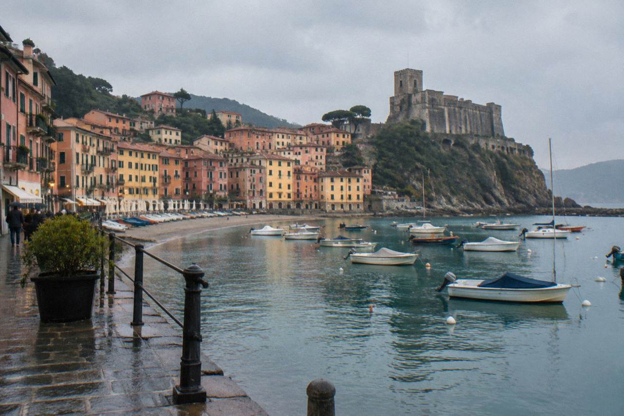 Colourful houses above a small harbour with boats and a hilltop castle