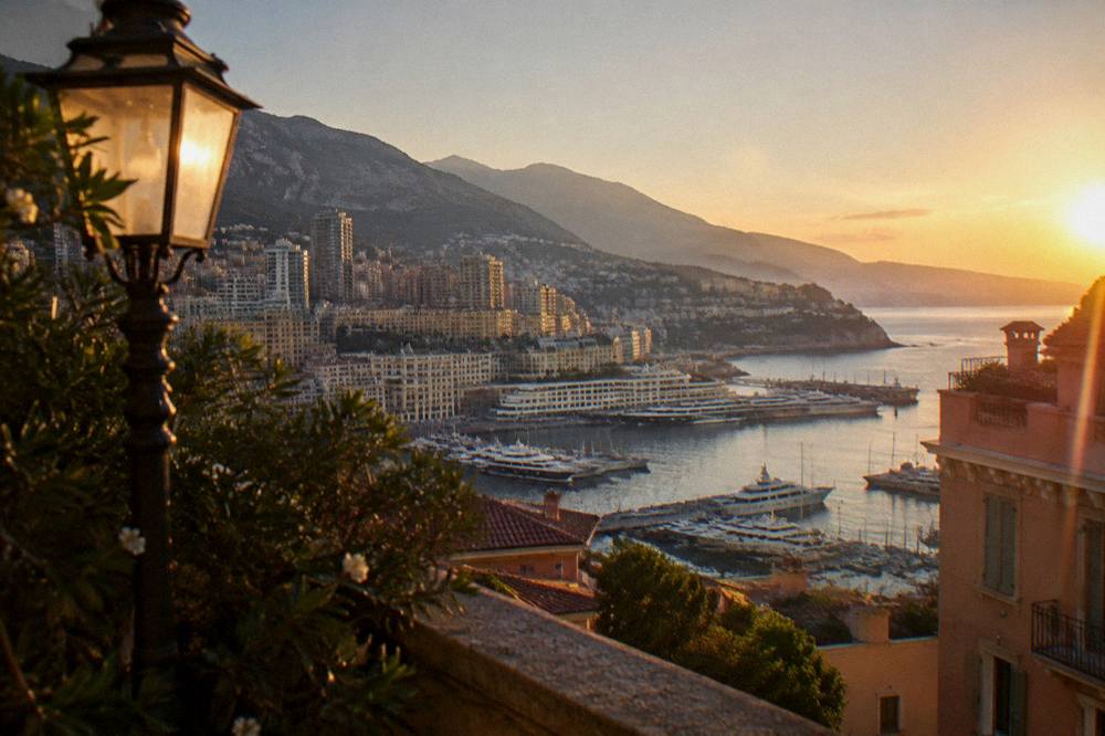Sunset over a coastal city with a harbour and distant mountains