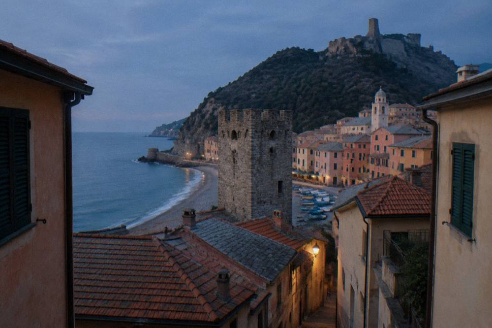Tiled rooftops and a stone tower seen from above a narrow coastal street