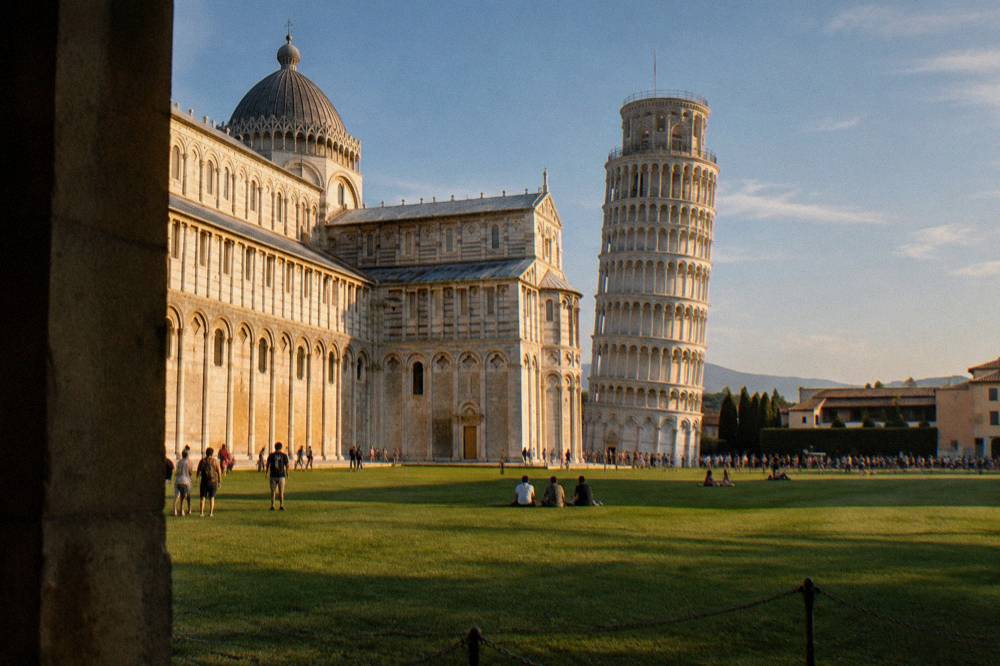 Tourists gathered on the lawn in front of the cathedral and leaning tower