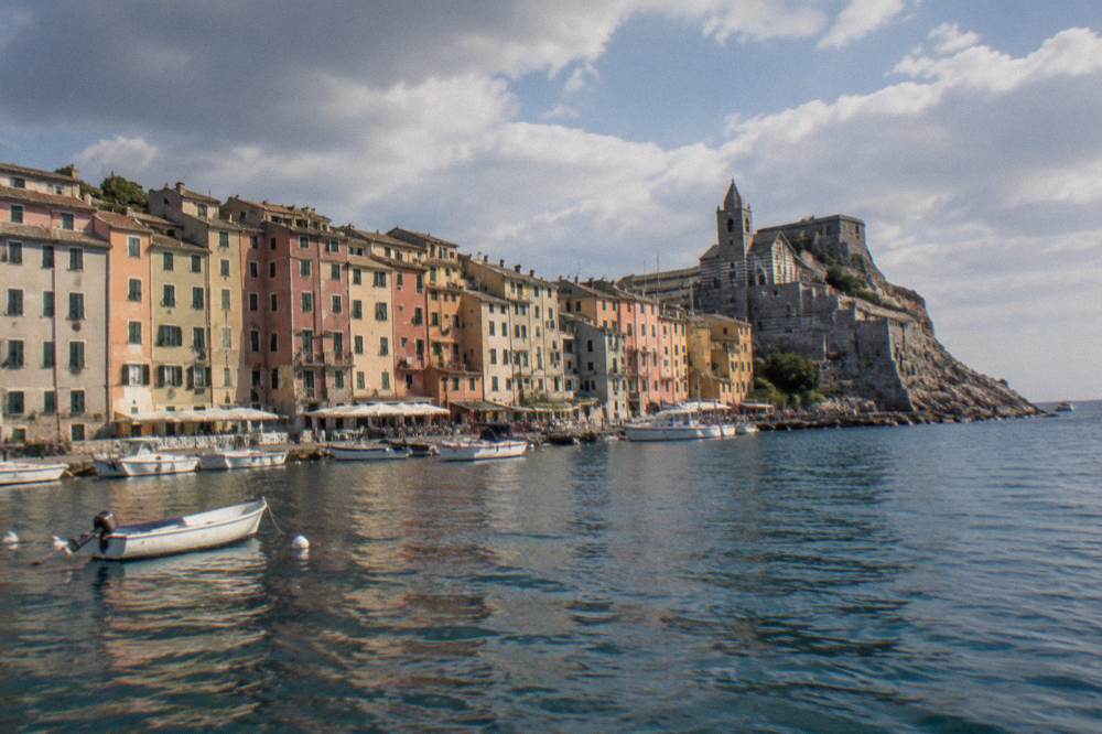 A village waterfront seen from the water, with boats moored beside colourful apartment buildings