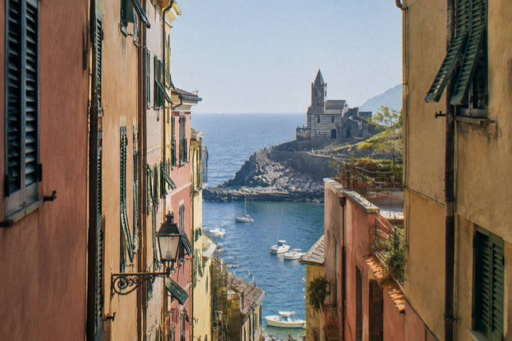 Narrow village street between tall pastel-coloured buildings with shutters