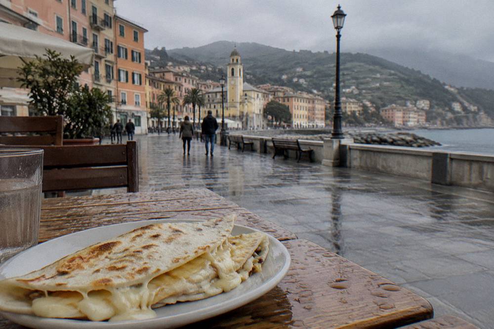 A plate of thin flatbread filled with melted cheese on a wooden table
