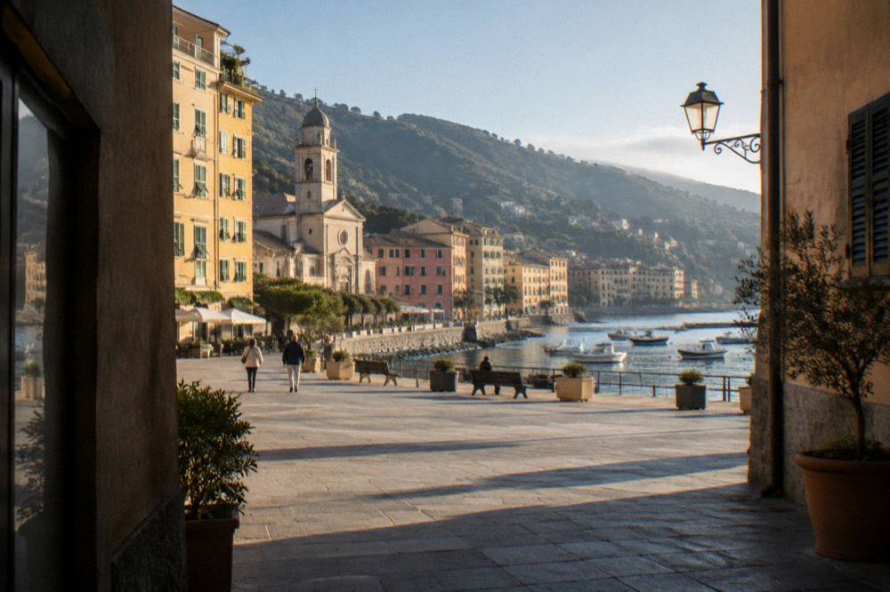 Evening light over a small Ligurian harbour with boats at anchor and hills behind