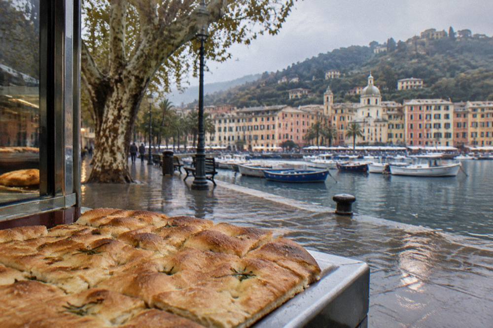 Flat focaccia bread with a thin crisp surface on a bakery counter