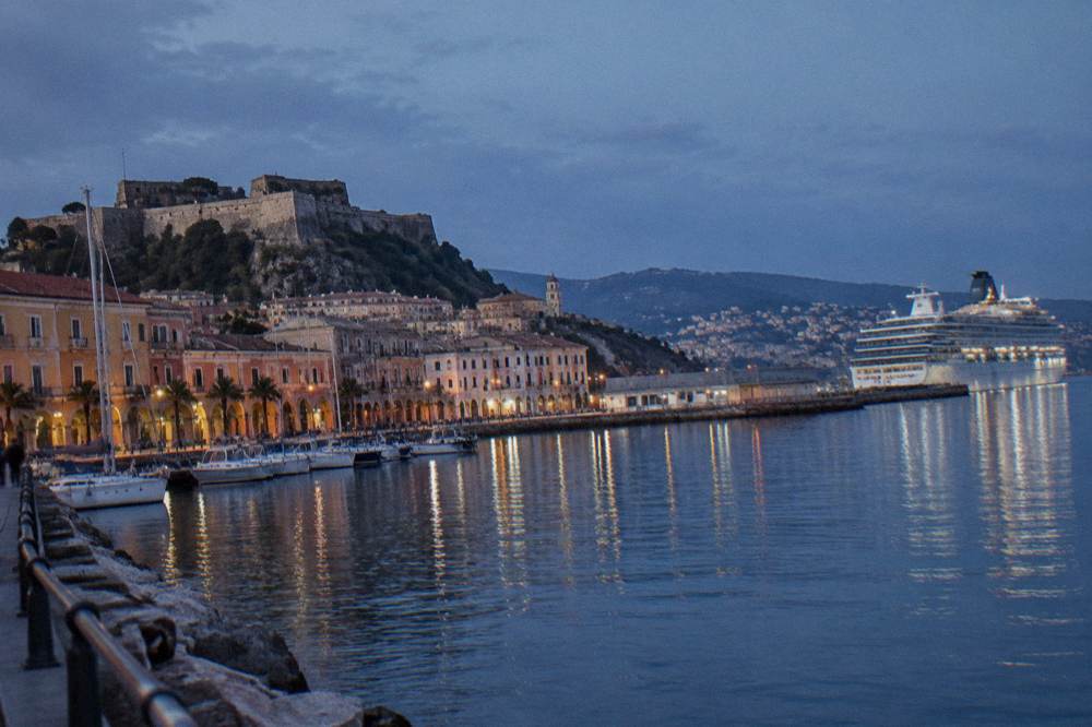 A cruise ship docked at a terminal with a harbour town behind it