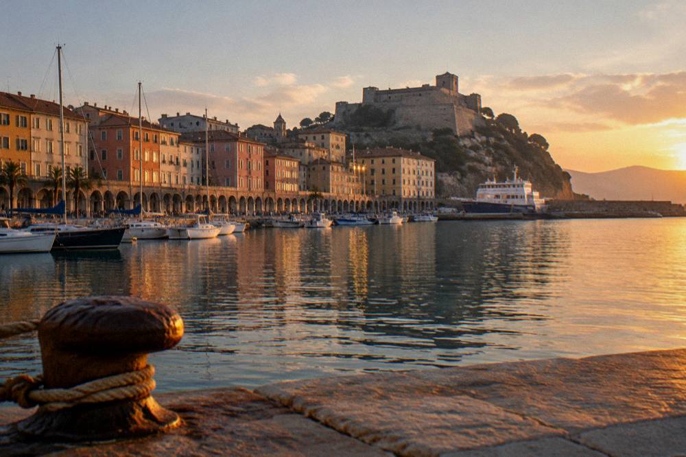 An evening view over a Ligurian harbour with a fortress silhouette on the hill