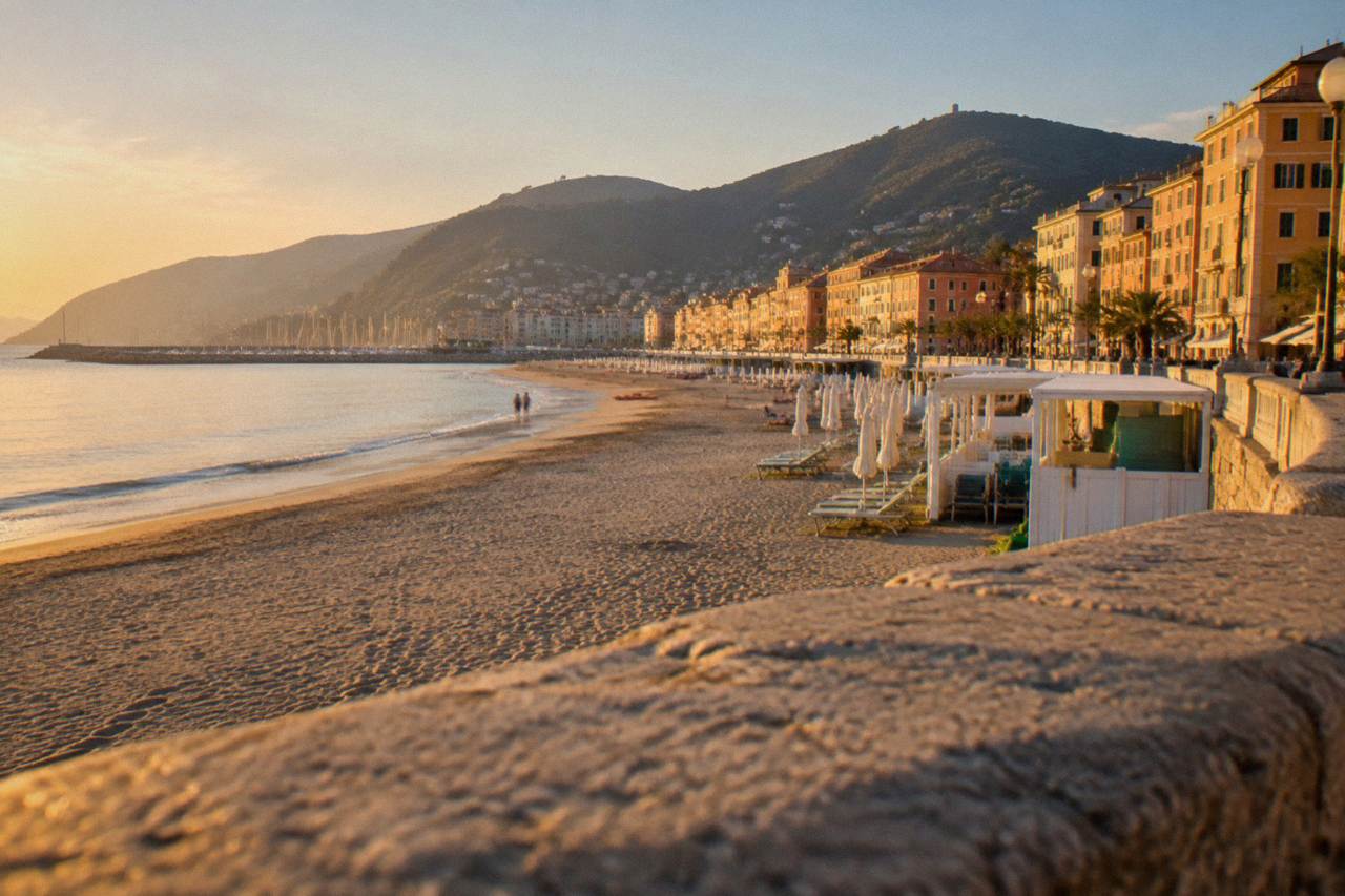 A seaside promenade on the western Ligurian coast with beach establishments and calm sea