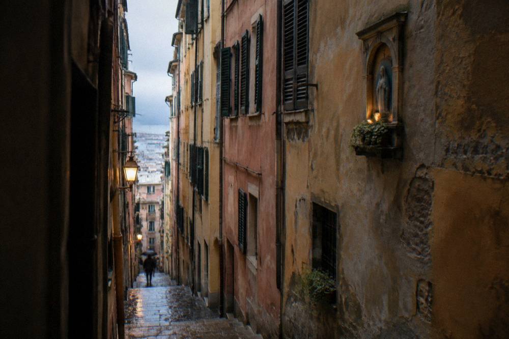 A narrow caruggi lane in Genoa's old town with tall coloured buildings