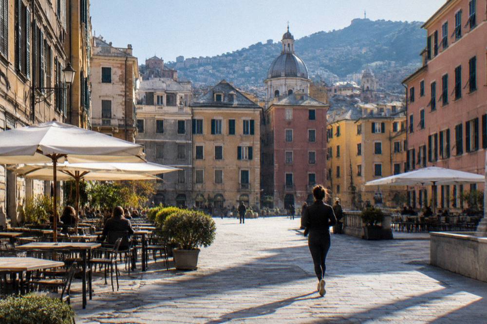 A sunny square in Genoa with outdoor cafe tables and historic buildings