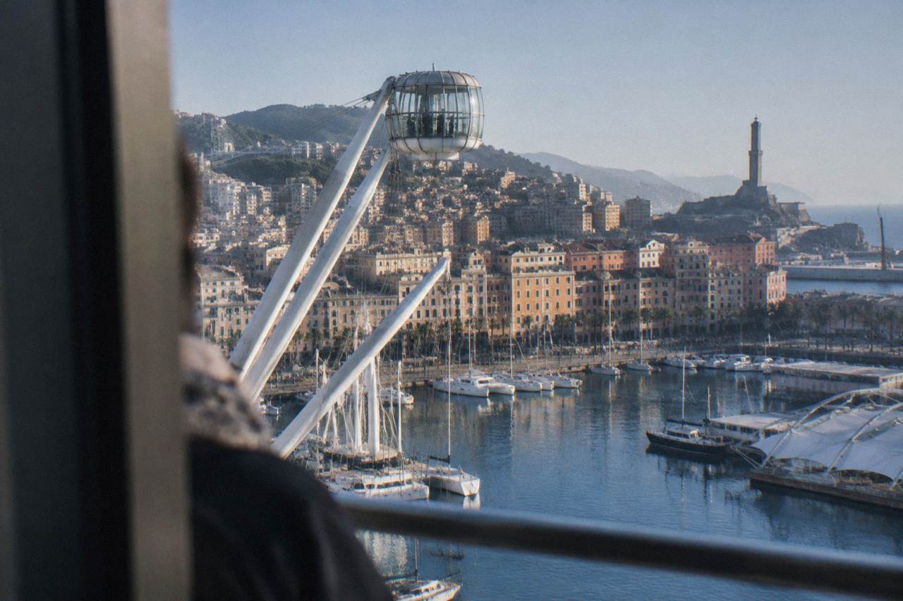The Porto Antico harbour of Genoa with boats, the Bigo lift and the Lanterna lighthouse under a clear sky