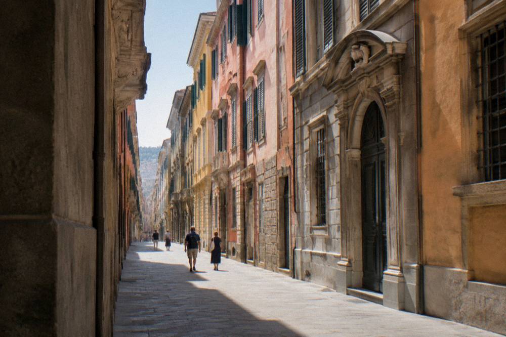 Visitors walking past the grand facades of Via Garibaldi in Genoa