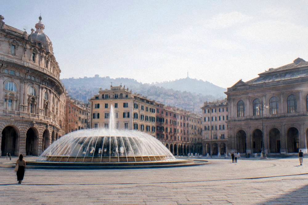 Piazza De Ferrari with its fountain and surrounding buildings in evening light