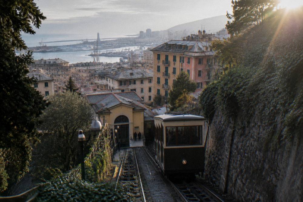 A funicular carriage climbing a hillside track above lit city rooftops