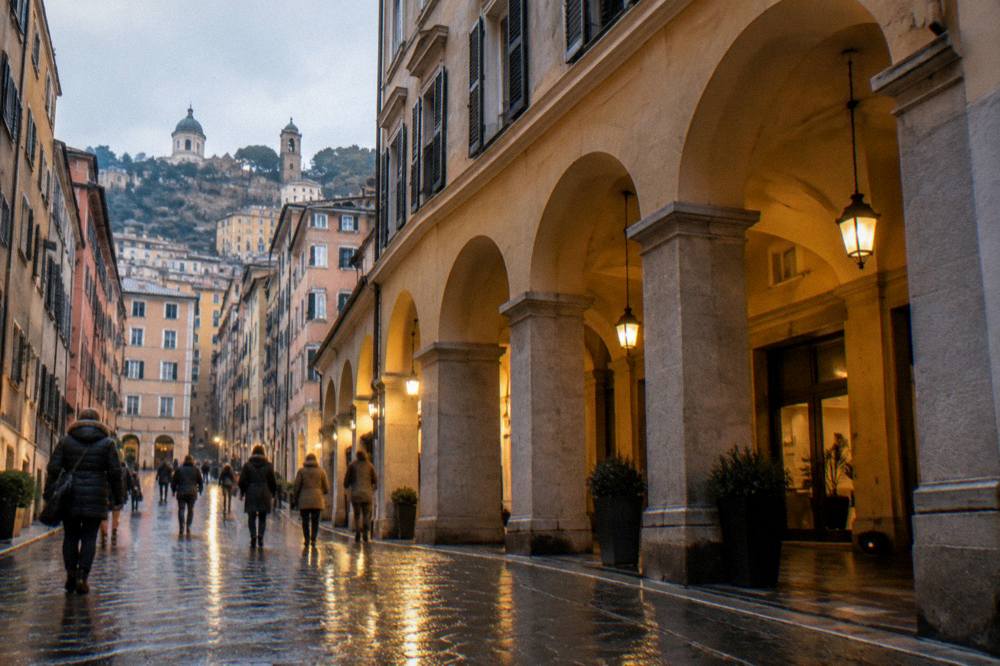 A lit hotel arcade and evening street scene in central Genoa