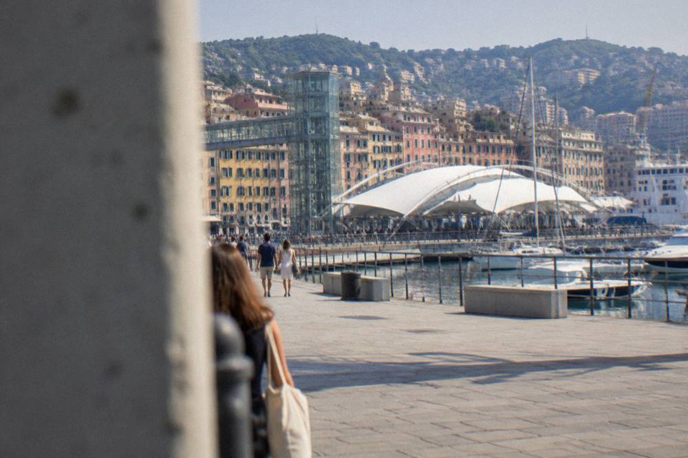 The Porto Antico old harbour of Genoa with a panoramic lift structure and ships at the docks