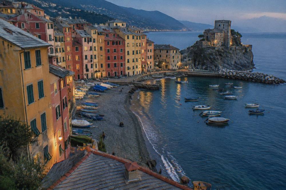 Colourful tall buildings above a small harbour with fishing boats in Camogli