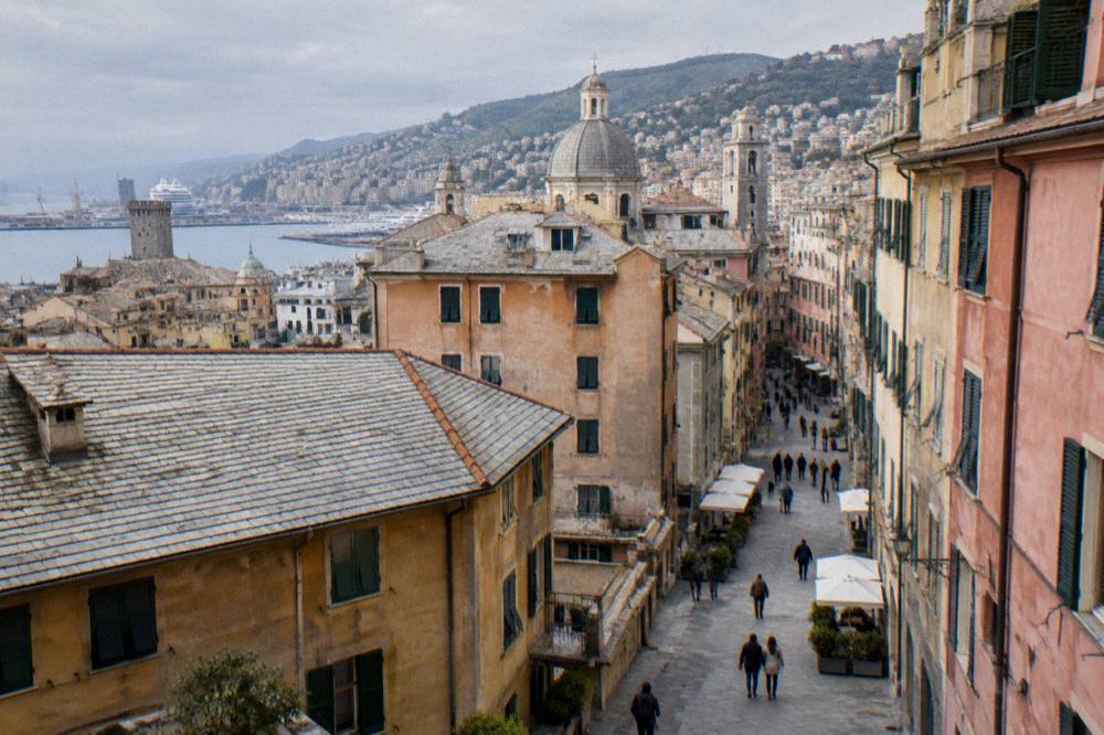 People walking along a bright street of historic buildings in central Genoa