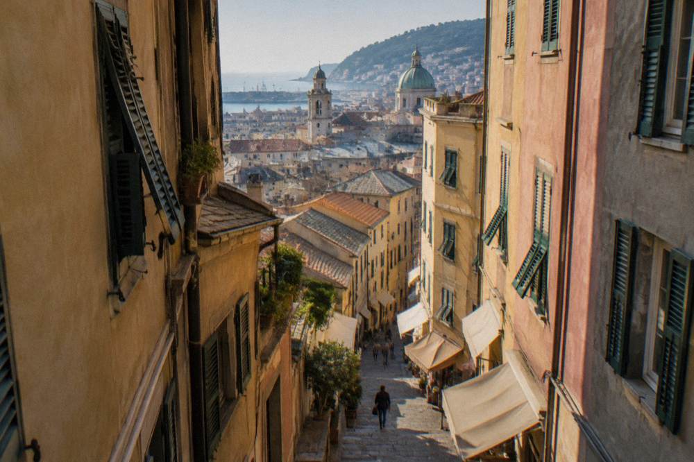 A narrow medieval lane in Genoa with tall stone buildings and shop awnings