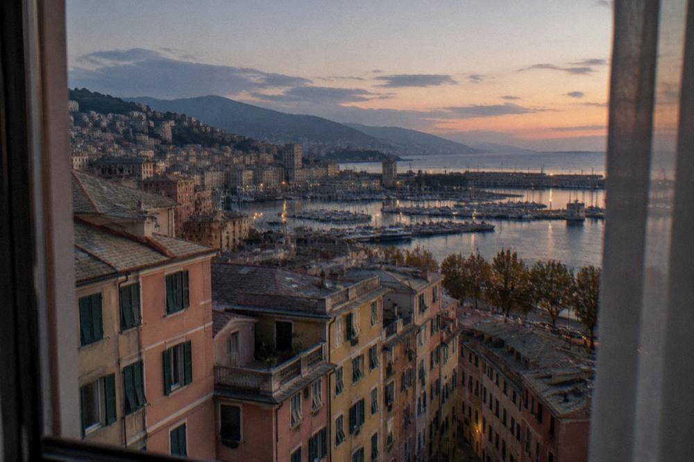Hotel room window overlooking a Mediterranean harbour at dusk