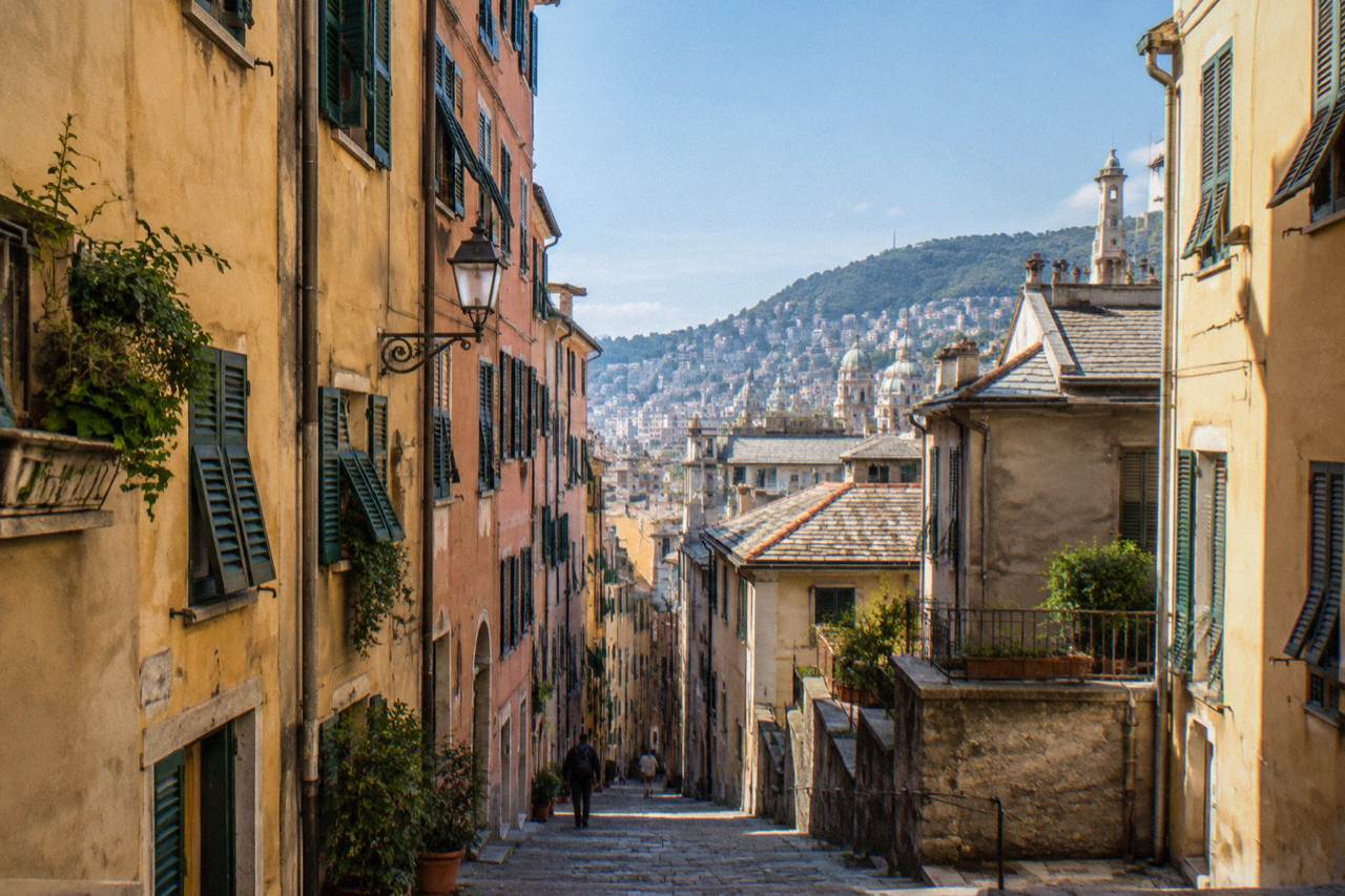Narrow medieval lane in the old town of Genoa with tall painted buildings on both sides