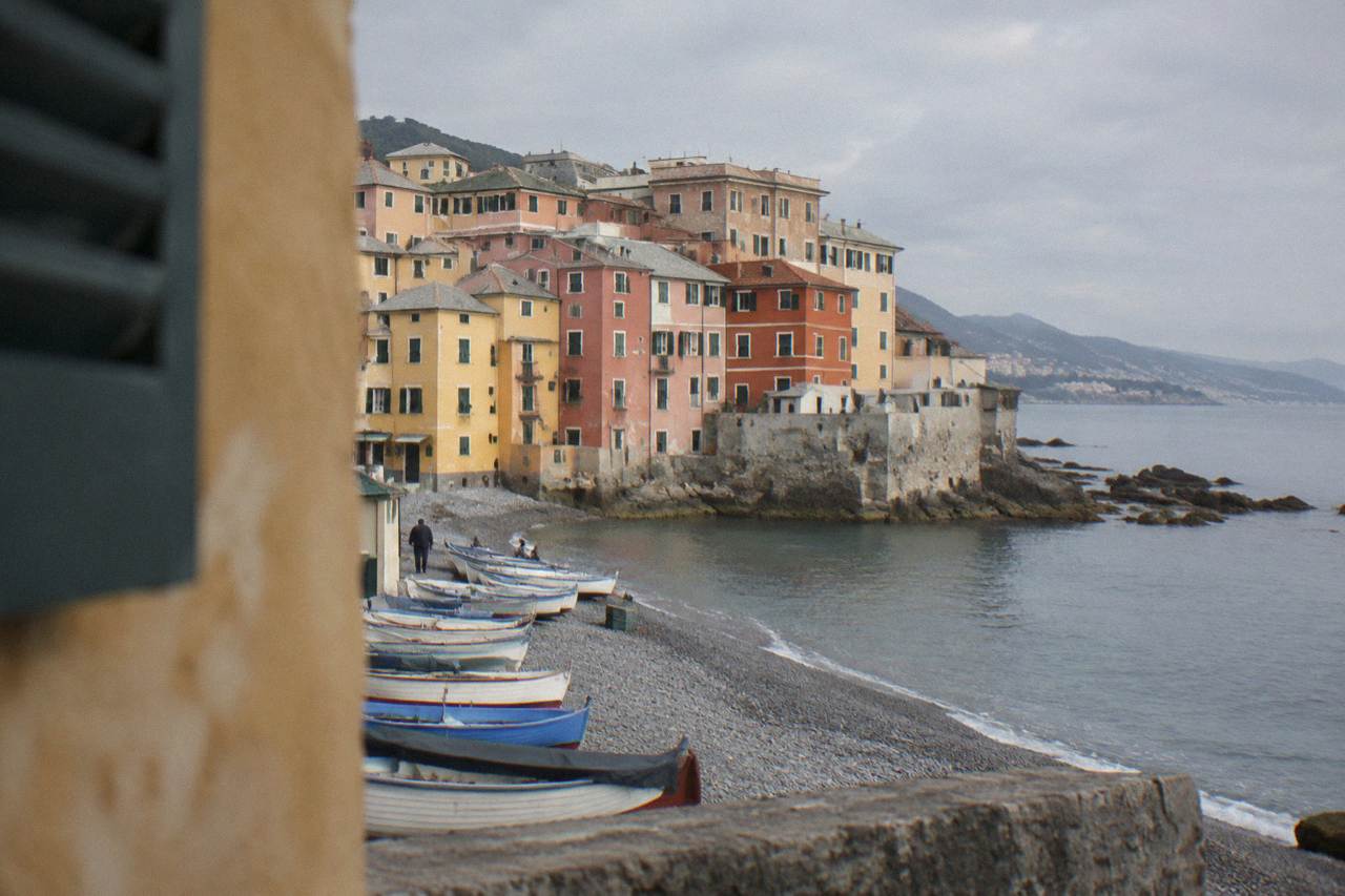 Colourful houses of Boccadasse rising above a small pebble beach with fishing boats