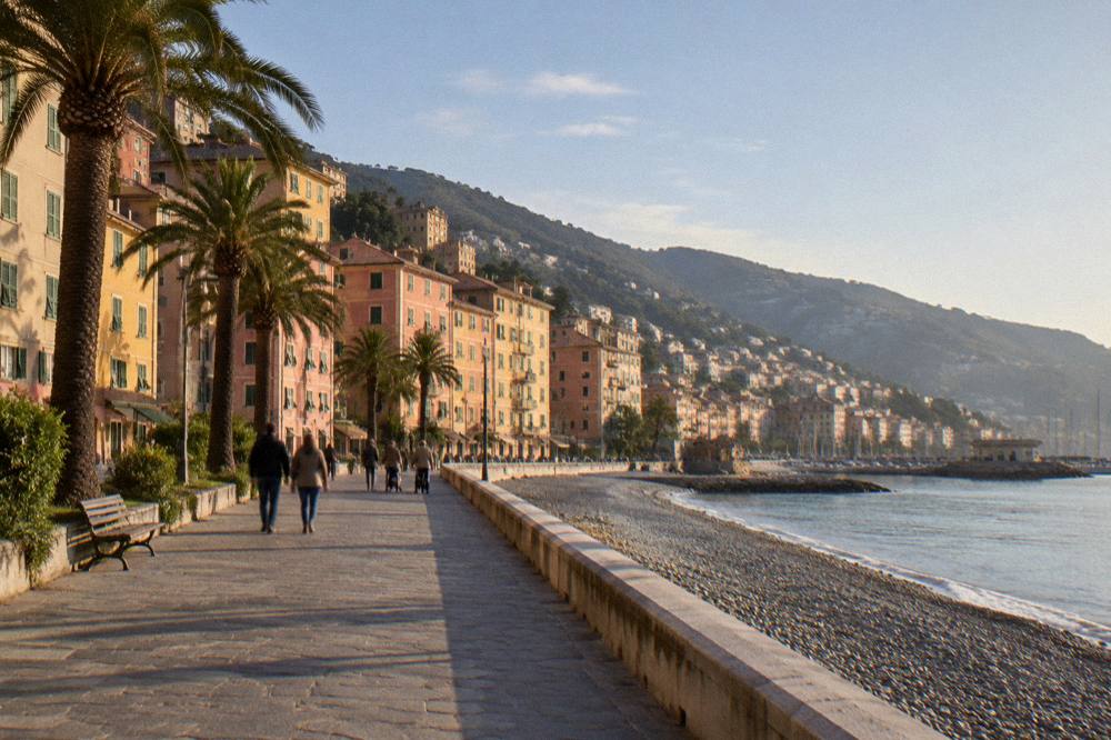 Wide view of a seaside promenade with palm trees and people walking beside the water