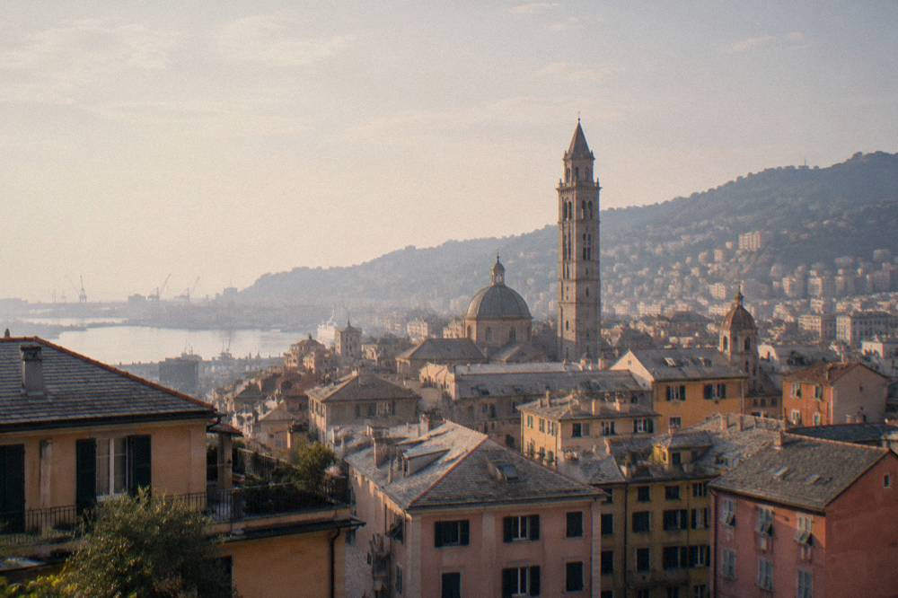 Bell tower of a Genoa church seen above rooftops at dusk