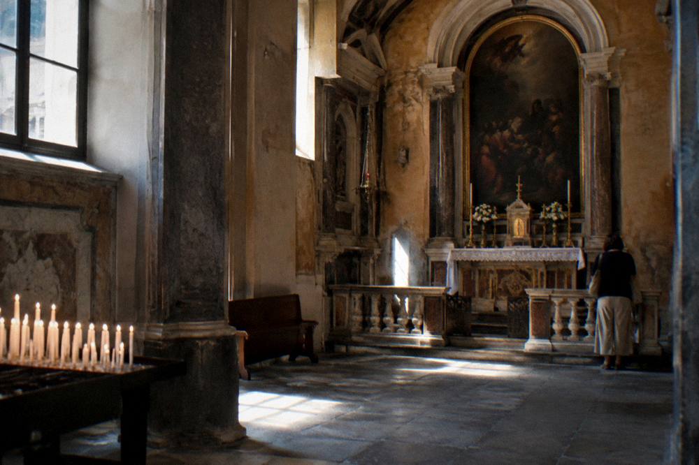 Sunlit interior of a church in Genoa with side chapel and stone floor