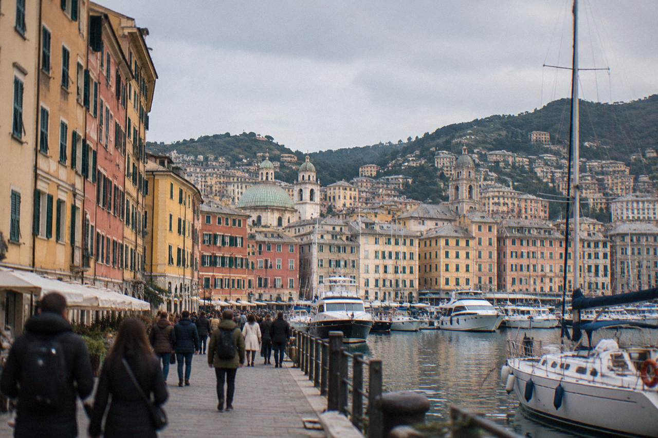 Crowds walking along the old harbour of Genoa with boats and exhibition tents along the waterfront