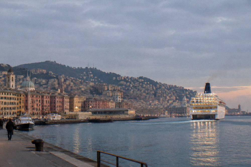 Overnight ferry lit up and departing the Genoa harbour at dusk