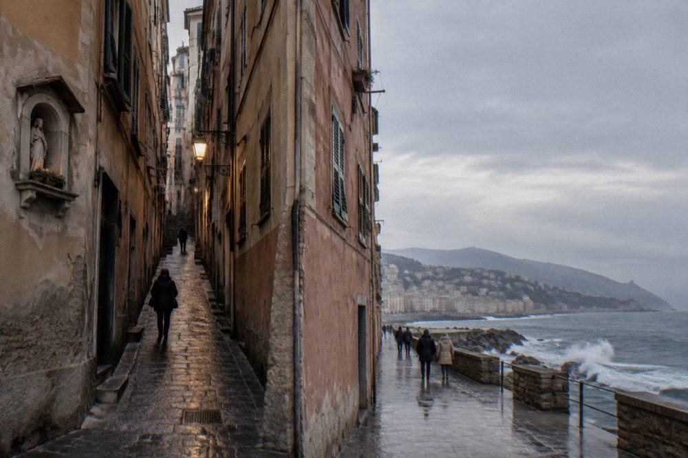 Waves breaking against a stone seafront promenade on a grey day on the Ligurian coast