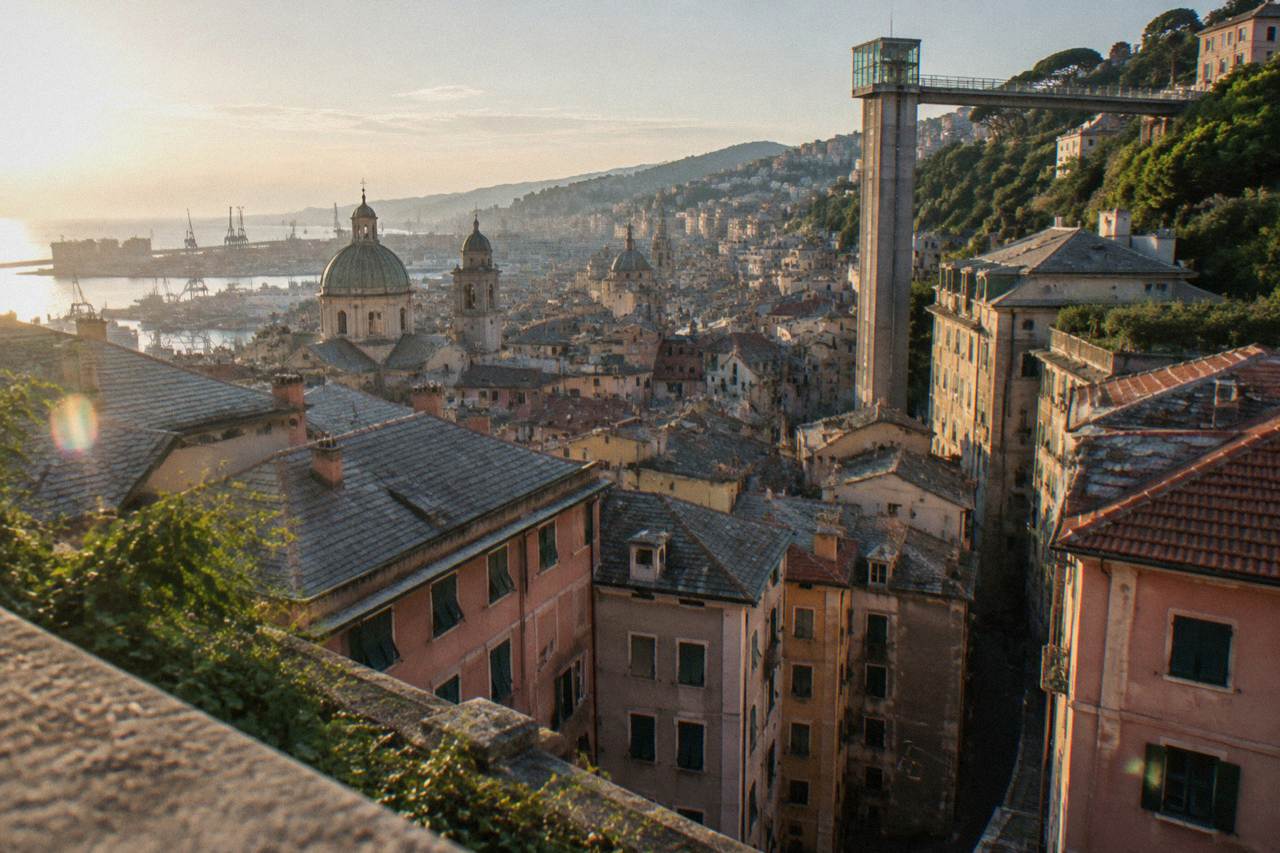 A public lift tower rising above the rooftops of Genoa toward a hillside terrace