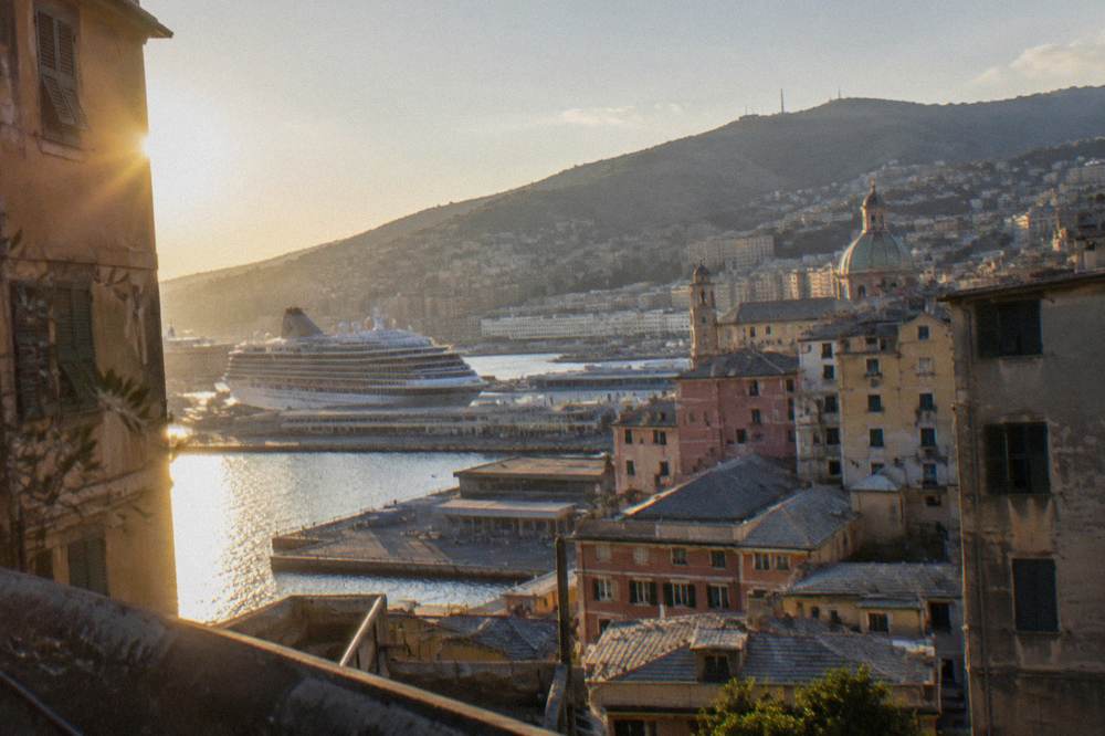 Cruise ship docked at a Genoa terminal with the city hills rising behind