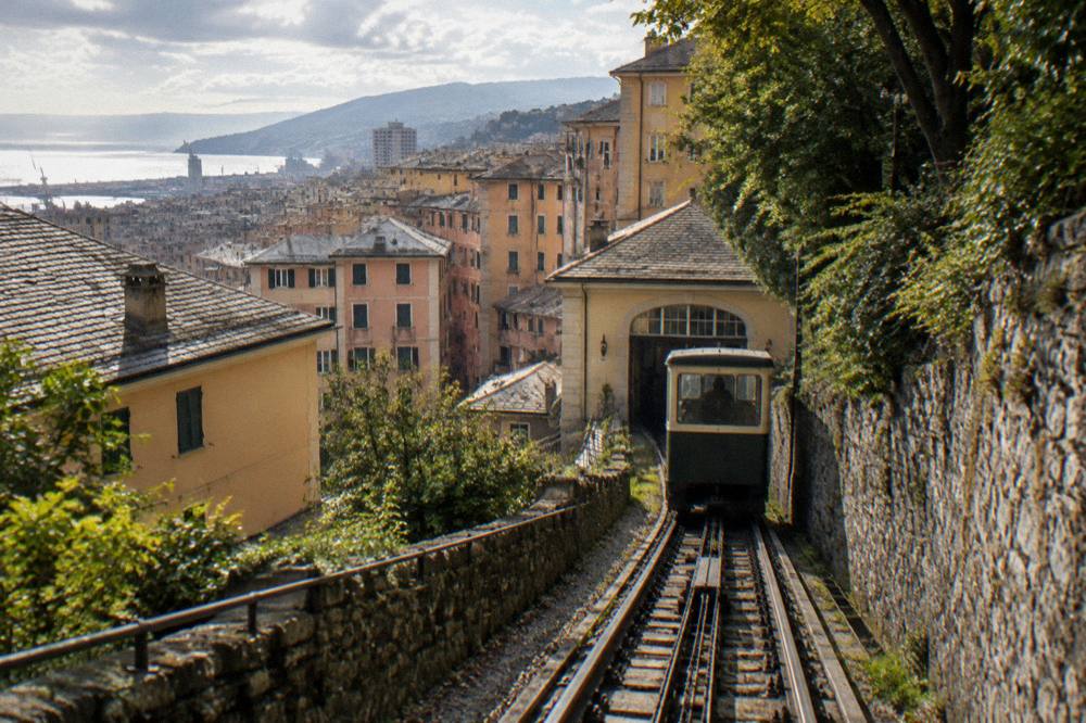 Funicular cabin climbing through Genoa rooftops toward the hillside