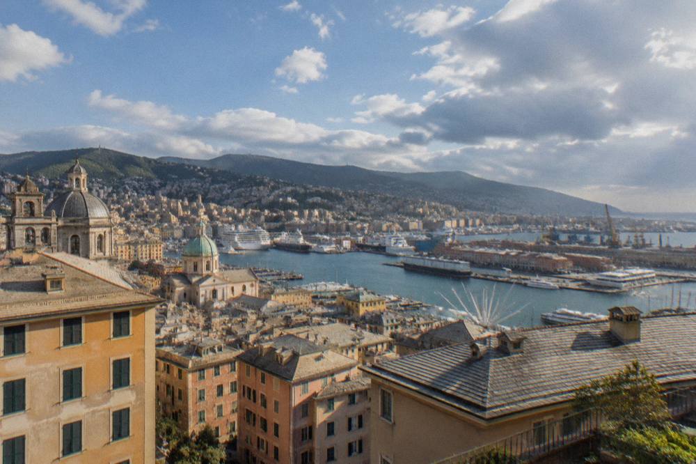 Aerial view of Genoa's harbour with ships moored along the waterfront and hills behind the city